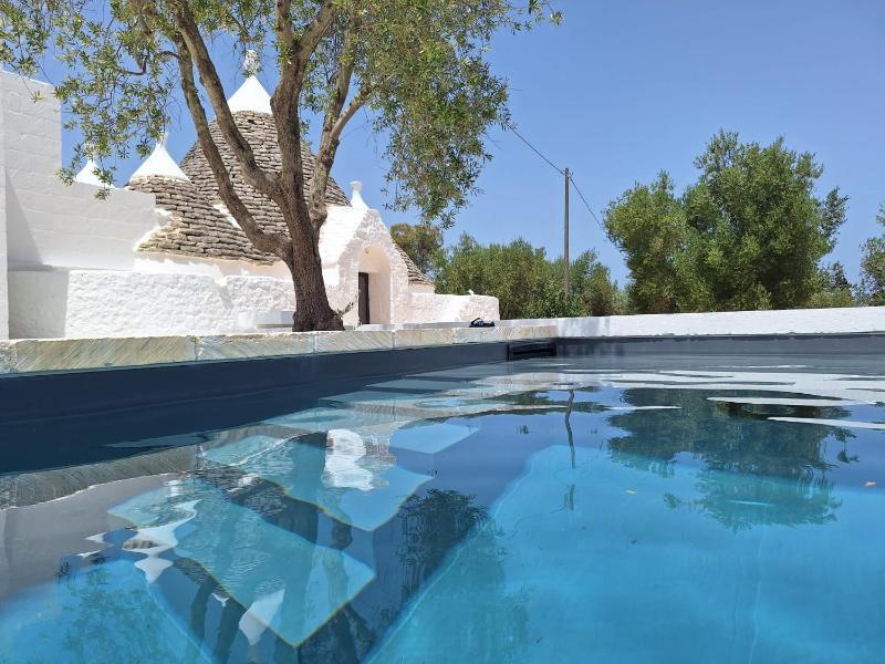 Trulli au milieu d'un champ d'oliviers avec piscine
