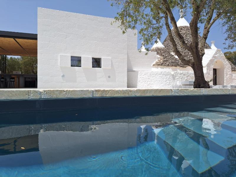 Trulli au milieu d'un champ d'oliviers avec piscine