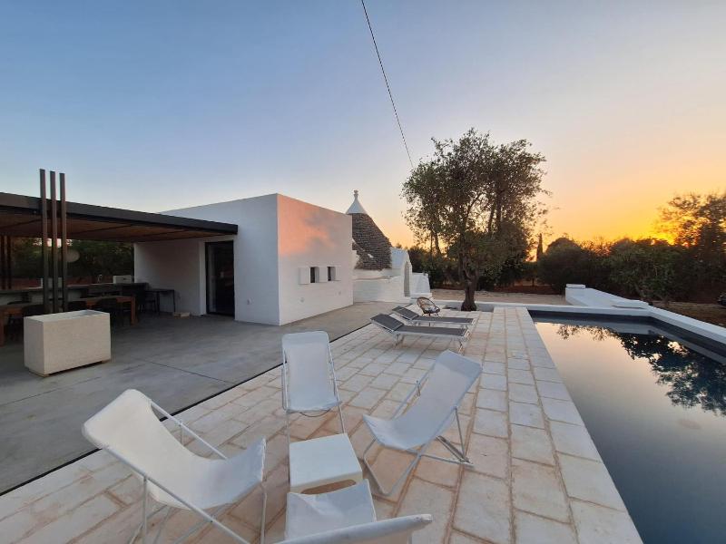 Trulli au milieu d'un champ d'oliviers avec piscine