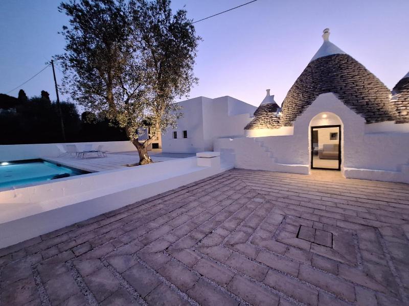 Trulli au milieu d'un champ d'oliviers avec piscine